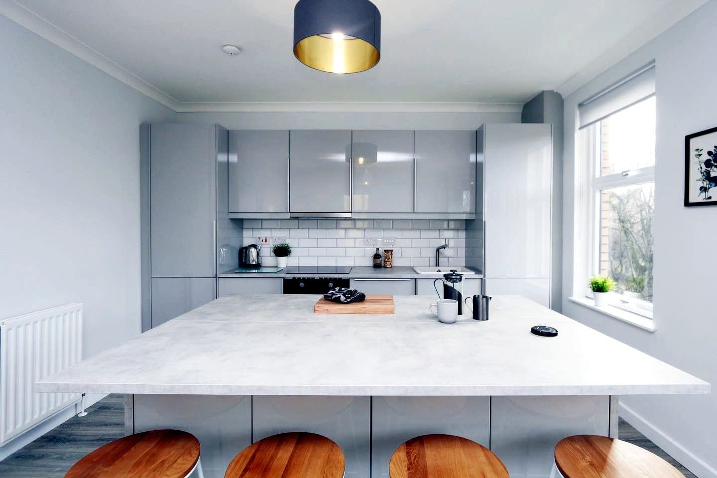Fitted grey kitchen with breakfast island and oak stools
