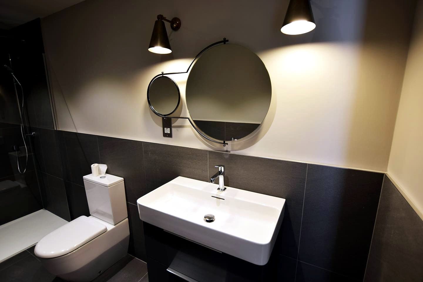 Bathroom vanity with round mirror and wall lights