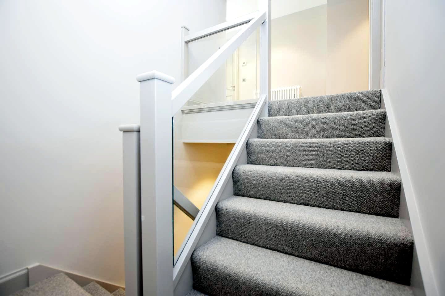 New staircase with glass balustrade and grey carpet